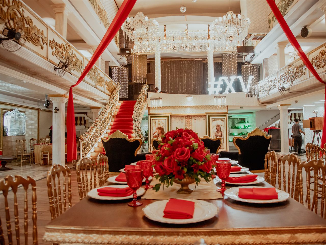 Mesa posta em dourado e vermelho no salão do Palace Hall, com a escadaria ao fundo